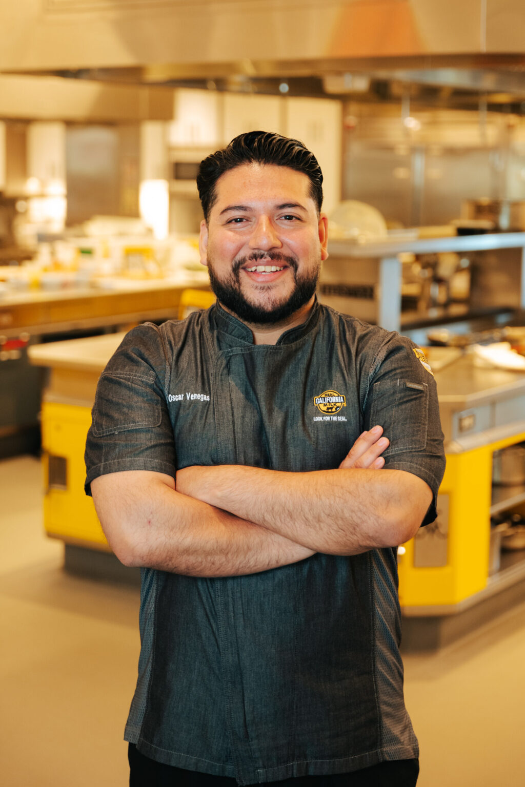 Oscar Venegas, food industry professional, smiling in commercial food distribution warehouse with modern food processing equipment.