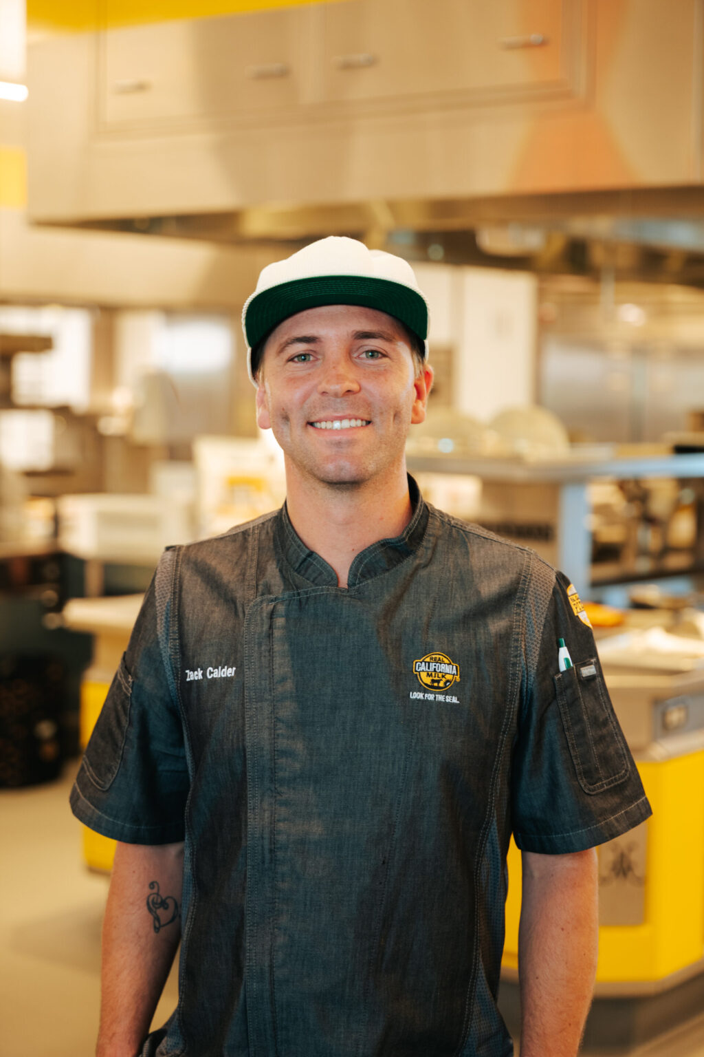 Portrait of smiling food industry employee in denim uniform at wholesale food distribution facility warehouse.