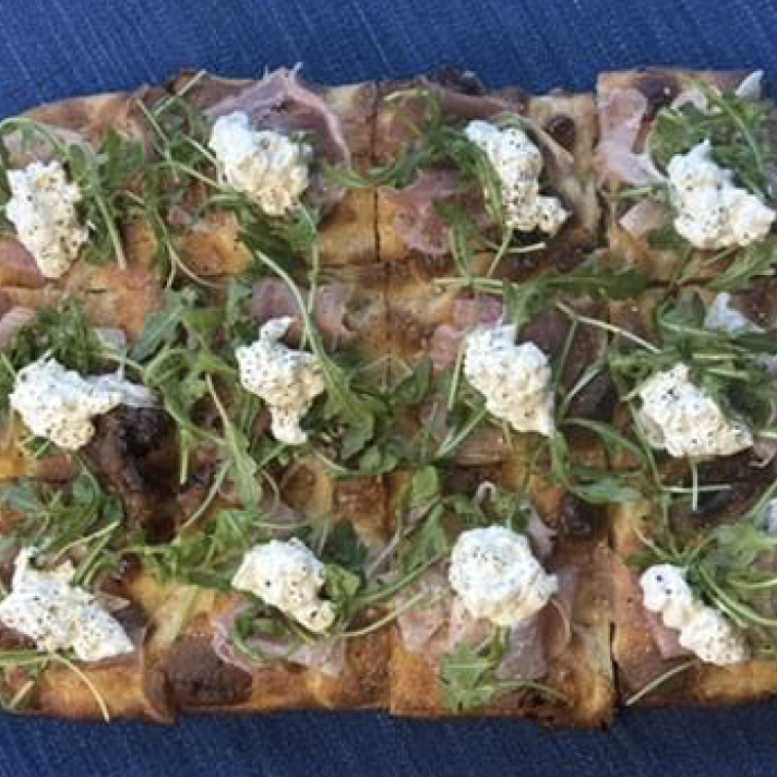 Artisan flatbread topped with creamy ricotta cheese, fresh microgreens, and herbs, ideal for upscale food service and wholesale catering suppliers.
