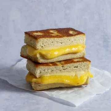Golden-brown toasted focaccia bread sandwich with melted cheese and scrambled eggs, ideal for foodservice and wholesale food suppliers.