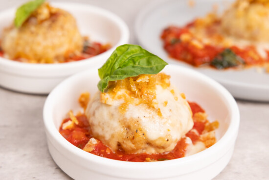 Cheesy dumplings served in tomato sauce, garnished with fresh basil for a delightful taste.