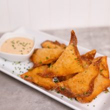 Crispy fried wontons served with a creamy dipping sauce and garnished with chives.