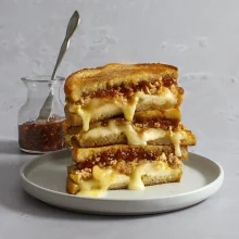Stacked gourmet sandwich featuring melted brie cheese, caramelized onions, and toasted bread, ideal for foodservice and wholesale food distribution.