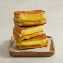 Stacked grilled cheese sandwiches with melted cheddar cheese and golden-brown bread crusts, ideal for foodservice and wholesale distribution.