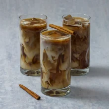 Three tall glasses of iced cinnamon latte with swirled cream and cinnamon stick garnish, ideal for commercial food and beverage suppliers.
