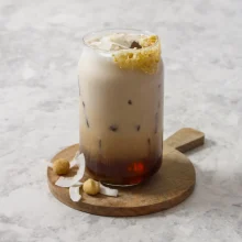 Creamy iced coconut macadamia latte with caramel drizzle rim and coconut garnish, perfect for foodservice and beverage distribution.