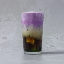 Vibrant layered pandan ube latte with purple, cream, and dark espresso layers in a ribbed glass, ideal for specialty beverage foodservice suppliers.