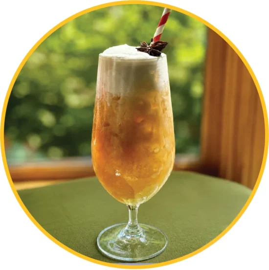 Refreshing iced chai latte in a tall glass with whipped cream and star anise garnish, perfect for foodservice beverage programs.