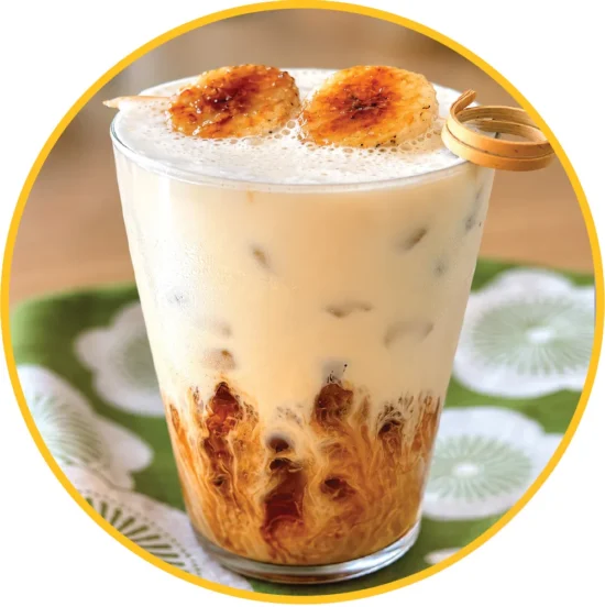 Korean banana milk latte with creamy topping and caramelized banana garnish, ideal for wholesale food distribution and commercial beverage suppliers.